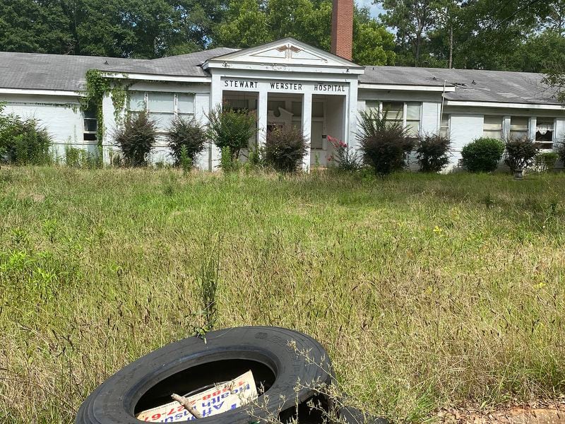 Eight years ago, Stewart Webster Hospital, in a financial tailspin, closed its doors for the last time. Now weeds and trash litter the grounds around the facility. (Andy Miller / Georgia Health News)