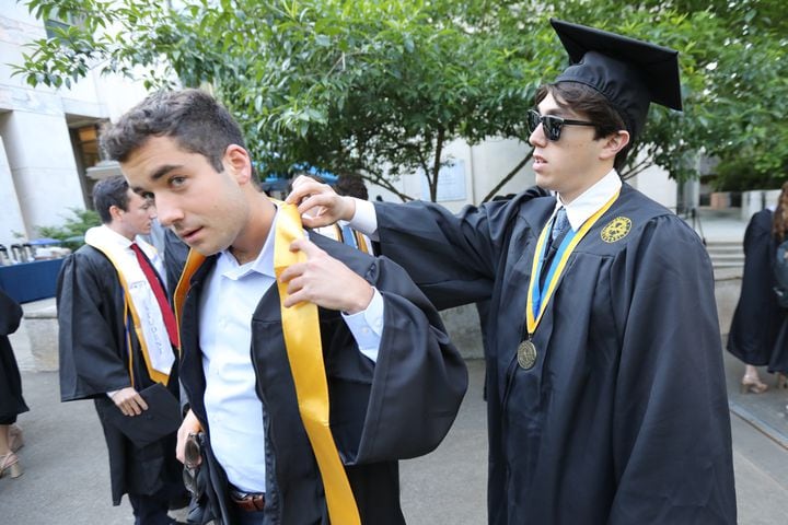 Jared Feuer (right) helps Jefferey Javin put the band around his neck moments before the start of the ceremony during Emory University’s 2022 Commencement on Monday, May 9, 2022. Miguel Martinez /miguel.martinezjimenez@ajc.com