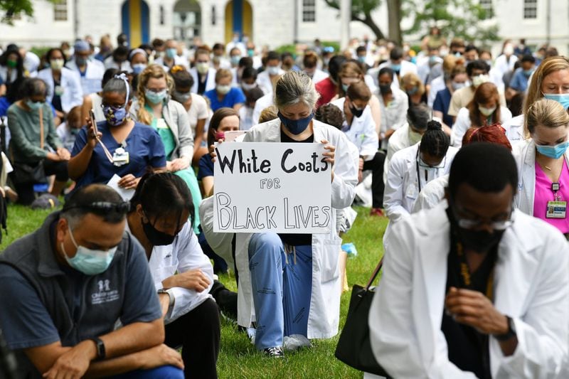 Emory medical students, doctors, nurses and other health care staff take a knee for eight minutes and 46 seconds in memory of George Floyd ‘and countless others,’ in a demonstration they call White Coats for Black Lives at Emory University Quadrangle on Emory University campus in Decatur on June 5, 2020. Doctors these days are finding themselves at the intersection of America’s race debate: giving advice to protesters on how to protect their eyes from tear gas and speaking their frustration at seeing people of color disproportionately sickened by COVID-19. HYOSUB SHIN / HYOSUB.SHIN@AJC.COM