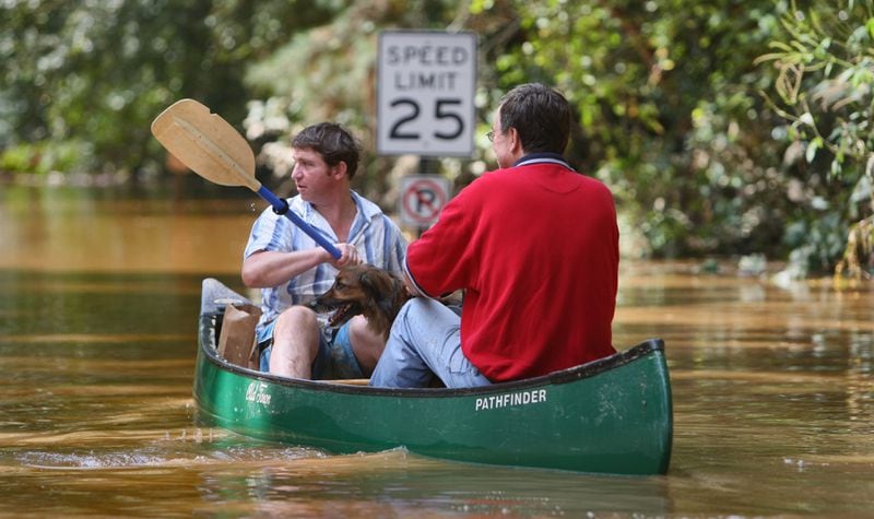 Paddling down Paces Ferry Drive, Ben Prince (left) used his canoe to ferry neighbor, Jim Hobbs and his dog, Dylan (right) to and from their home as they gathered supplies. Vinings residents and business owners were dealing with a major flooding issue Tuesday, September 22, 2009 as the Chattahoochee River made its way along the banks near Paces Ferry Road. Many residents with upscale homes were hit hard, some for the second time since an earlier post millennia flooding episode. Since early Monday, seven lives have been taken and several other people remain missing. The record-setting rains also have closed schools and roads and have left people stranded in their homes. The river’s level near Vinings was at 27.36 feet before daybreak Tuesday after cresting at 28.1 feet overnight. Flood stage is 14 feet, and anything above 20 feet is considered “major” flooding. The river was expected to slowly recede, falling below flood stage on Wednesday. The level overnight was the second highest on record, exceeded only by a crest of 29 feet in 1919. John Spink, jspink@ajc.com AJC FILE PHOTO