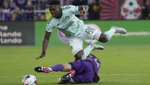Atlanta United midfielder Derrick Etienne (18) goes over Orlando City defender Kyle Smith, bottom, as they battle for possession of the ball during the first half of an MLS soccer match, Saturday, May 27, 2023, in Orlando, Fla. (AP Photo/John Raoux)
