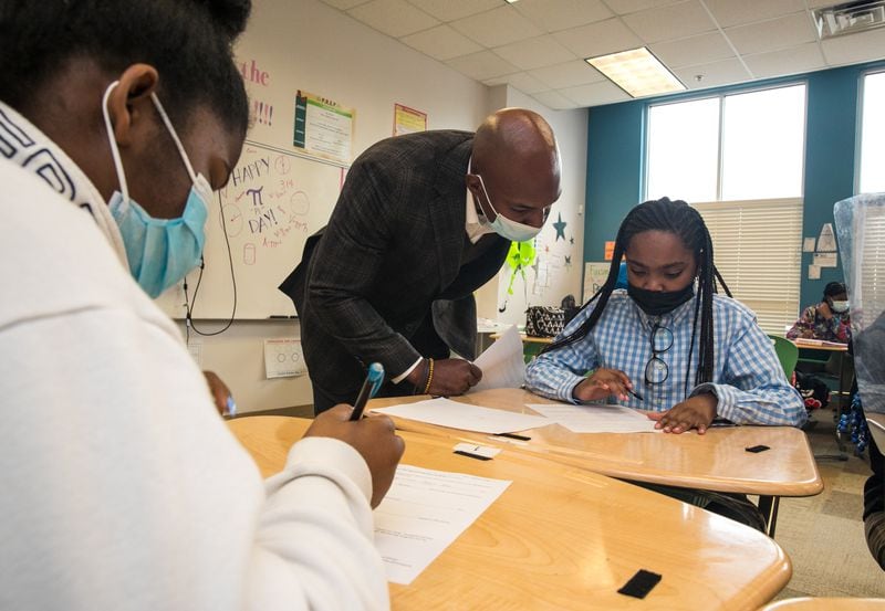 Joshua Byrd, center, a member of 100 Black Men, answers Katie Johnson’s question during a mentor program while Calise Hall, left, completes an icebreaker worksheet at Ivy Prep Academy aimed at preventing gun violence on Wednesday, March 16, 2022.  The program provides several weeks of after-school education in conflict resolution, personal choices, social media pitfalls and offers a student billboard competition while spreading awareness of gun violence.  (Jenni Girtman for The Atlanta Journal Constitution)