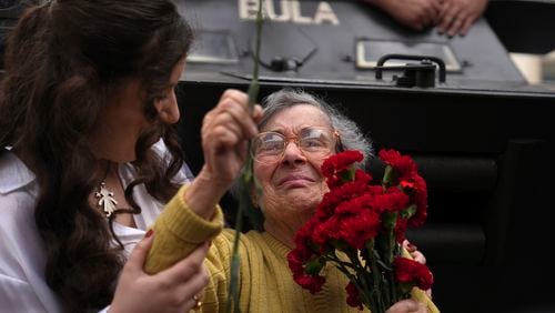 Celeste Caeiro, 90, holds a bunch of red carnations, in Lisbon, Thursday, April 25, 2024, during the reenactment of troops movements of fifty years ago, part of anniversary celebrations of the Carnation Revolution. Caeiro handed out red carnations to rebellious soldiers then, thus unwittingly naming the April 25, 1974 army coup that restored democracy in Portugal after 48 years of a fascist dictatorship. (AP Photo/Ana Brigida)
