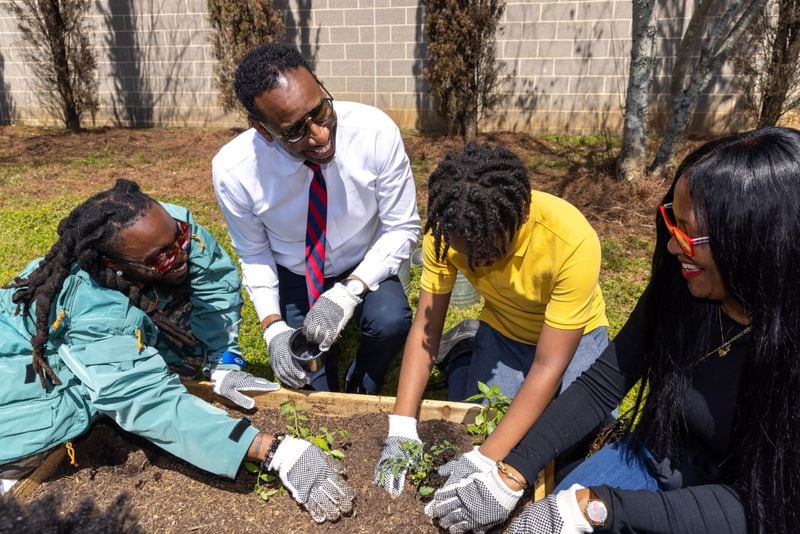 Olu aka Johnny Venus, Mayor Andre Dickens, and a student garden in a new community garden at Jean Childs Young Middle School in Atlanta on Thursday, March 30, 2023. Olu and WowGr8 aka Doctur Dot of hip-hop group Earthgang helped sponsor the project. (Arvin Temkar / arvin.temkar@ajc.com)
