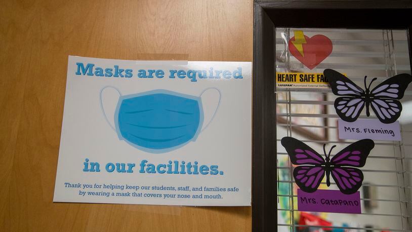 A sign requiring visitors to wear a face mask is displayed on the decorative front door to the Mill Creek High School clinic in Hoschton, Feb. 19, 2021. (Alyssa Pointer / Alyssa.Pointer@ajc.com)
