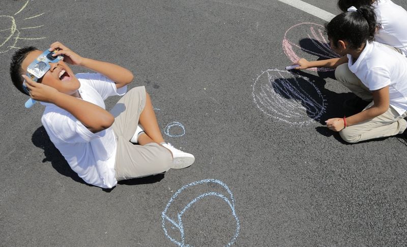 Gustavo Garcia and his fourth-grade class drew chalk drawings as the eclipse progressed. Woodward Elementary School in Atlanta held an eclipse viewing party as the entire school dressed in white and watched the event with solar eclipse glasses. BOB ANDRES /BANDRES@AJC.COM