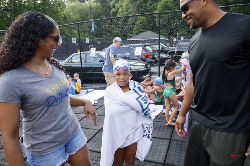 Maritza Correia Mcclendon (left), an Olympic medalist who now promotes swimming for blacks and hispanics, talks with her daughter, Sanaya, 8, along with Sanaya's father, Chad, after her race in a swim meet at Leslie Beach Club in Atlanta on Saturday, May 21, 2022.   (Bob Andres / robert.andres@ajc.com)