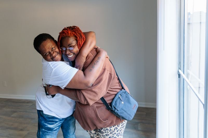 Synya Bradshaw, 52, and Maria Hairston, 35, who were previously unhoused, embrace during a portrait in their new apartment in Jonesboro on Thursday, November 3, 2022.   (Arvin Temkar / arvin.temkar@ajc.com)