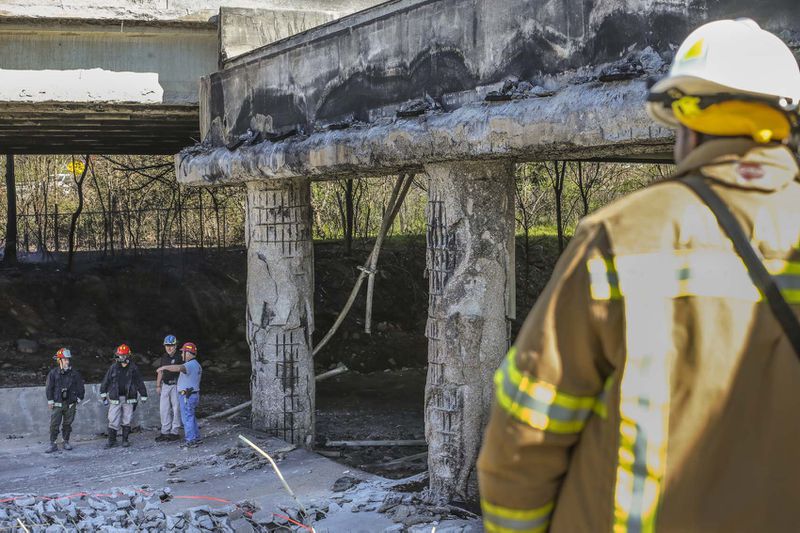 Atlanta firefighters remained on the scene putting out a smoldering fire Friday, March 31, 2017 at the I-85 collapse site while construction crews made their way into the zone to begin work. 