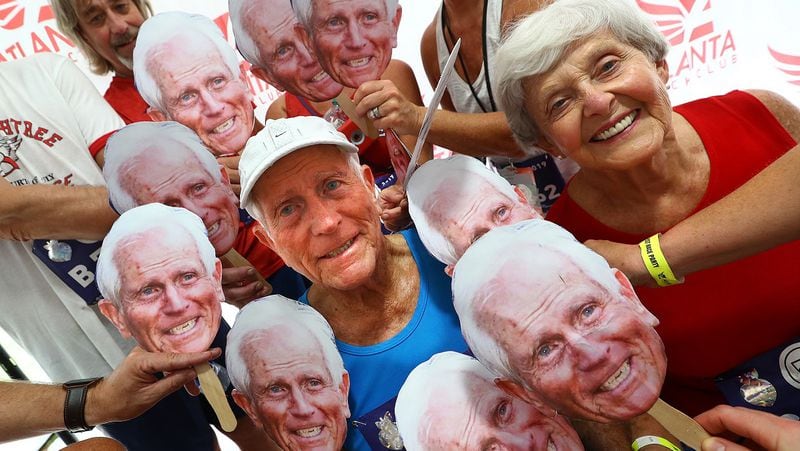 Bill Thorn, 89, and his wife, Patty, are surrounded by family and friends holding his picture at the conclusion of the 50th AJC Peachtree Road Race, having proved enough longevity to have run in every race since the inception.  Curtis Compton/ccompton@ajc.com