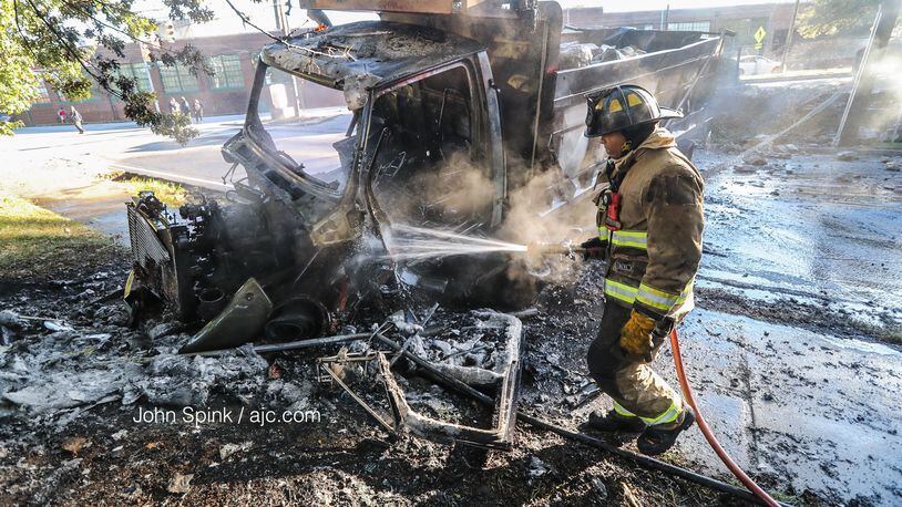 An Atlanta firefighter works to put out hot spots after a dump truck crashed into several vehicles, went over a 6-foot retaining wall and burst into flames in northwest Atlanta early Wednesday.