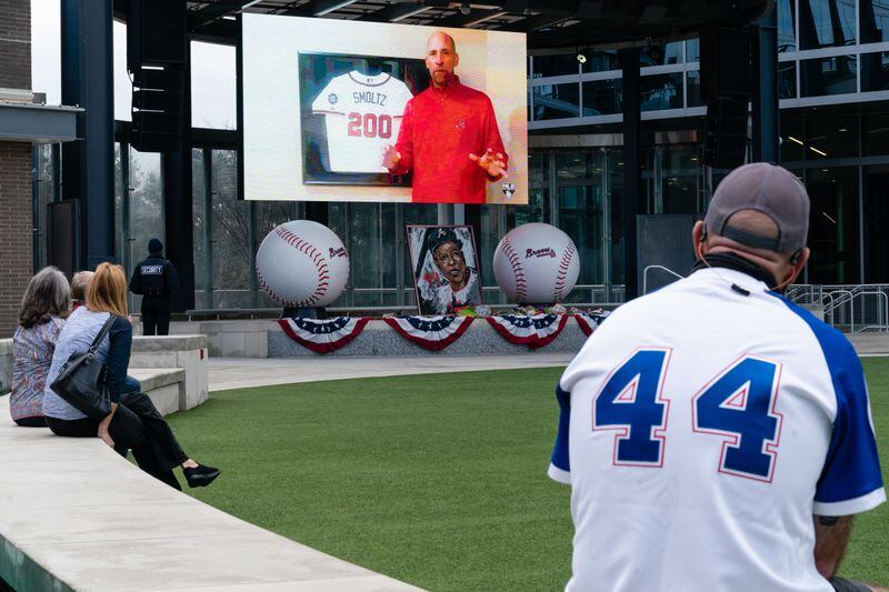 Fans gather outside Truist Park Tuesday to watch the broadcast of a memorial service honoring Braves Hall of Famer Hank Aaron at the ballpark in Atlanta. Aaron died last week at the age of 86. (Elijah Nouvelage/For the AJC)