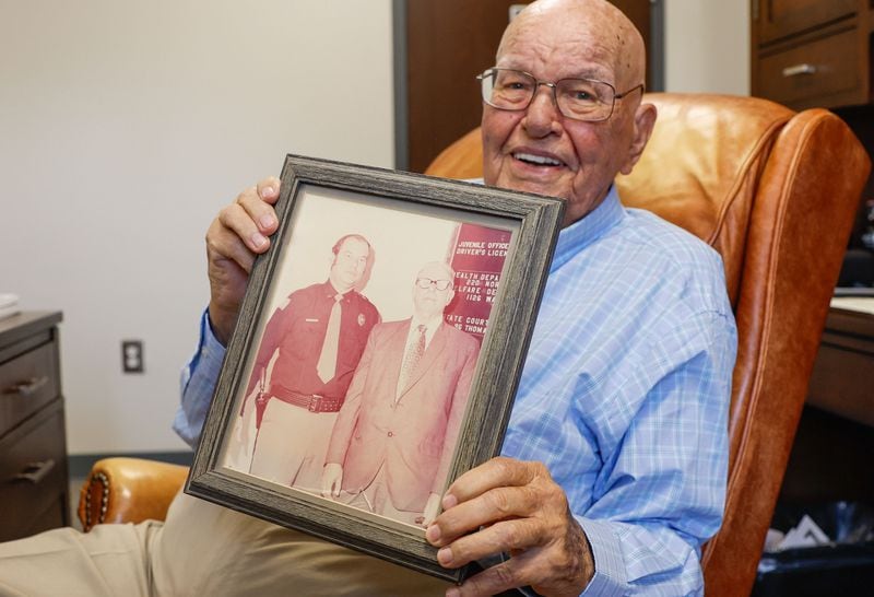 Talton shows off an old photograph of himself and his father, Cullen Talton Sr., on the day he became sheriff in 1973.  Staff photo by Natrice Miller/ AJC