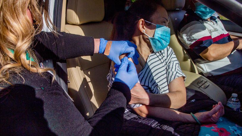 Phuong Pham, along with three family members, receives a COVID-19 shot during a drive-thru mass vaccination effort in Morrow on April 2.  (Steve Schaefer for The Atlanta Journal-Constitution)