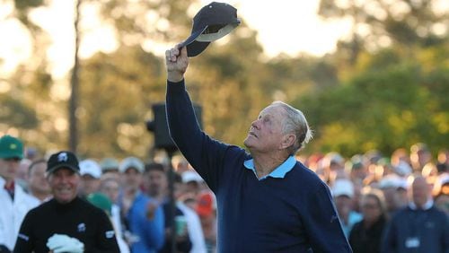 In a salute to the king of golf, Jack Nicklaus tips his hat toward heaven in honor of the late Arnold Palmer with Gary Player looking on while they hit their tee shots during the honorary start of the Masters at Augusta National Golf Club Thursday.