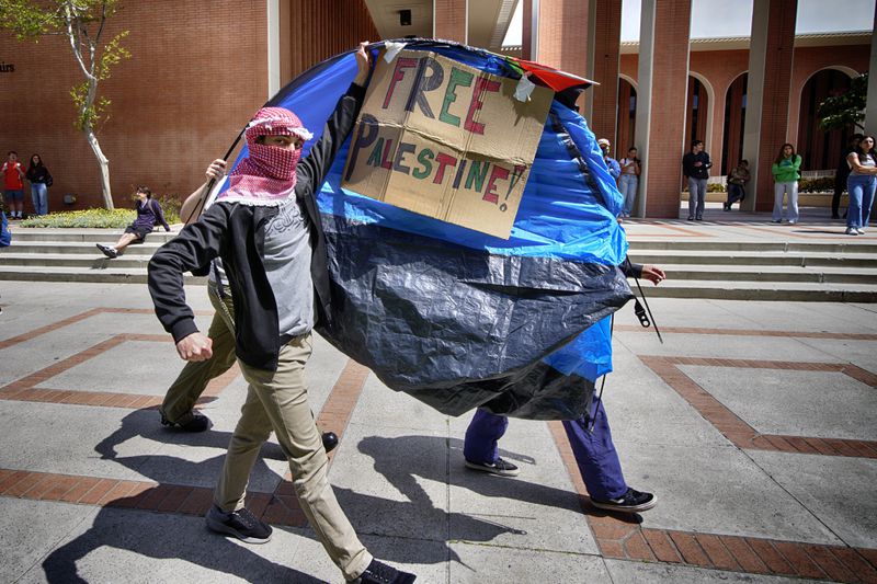 University of Southern California protesters carry a tent around Alumni Park on the University of Southern California to keep security from removing it during a pro-Palestinian occupation on Wednesday, April 24, 2024, in Los Angeles. (AP Photo/Richard Vogel)
