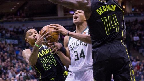 Milwaukee Bucks forward Giannis Antetokounmpo, center, is defended by Atlanta Hawks guard Kent Bazemore, left, and Dewayne Dedmon, right, during the first half of an NBA basketball game Tuesday, Feb. 13, 2018, in Milwaukee. (AP Photo/Darren Hauck)