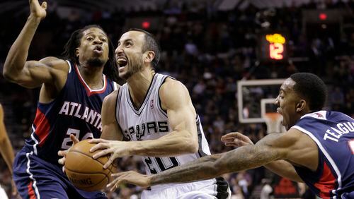San Antonio Spurs' Manu Ginobili, center, of Argentina, is pressured by Atlanta Hawks' Cartier Martin, left, and Jeff Teague, right, as he drives to the basket during the first half of an NBA basketball game, Monday, Dec. 2, 2013, in San Antonio.