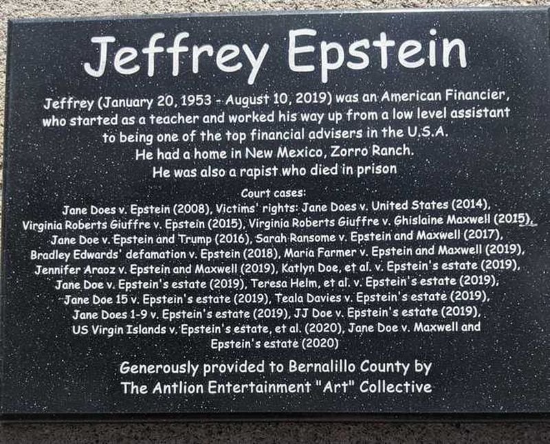 Below the makeshift statue of Epstein was a plaque that read in part: "He had a home in New Mexico, Zorro Ranch. He was also a rapist who died in prison," followed by a list of 18 court cases involving Epstein dating back to 2008. Ghislaine Maxwell's name also appears five times as a defendant.