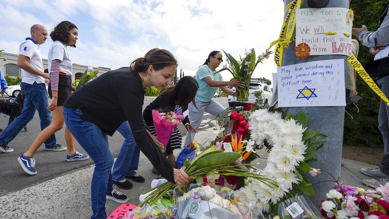 A group of Poway residents bring flowers and cards to a memorial outside of the Chabad of Poway synagogue, Sunday, April 28, 2019, in Poway, Calif. A man opened fire Saturday inside the synagogue near San Diego as worshippers celebrated the last day of a major Jewish holiday.