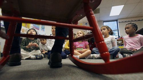 Kindergarten students in Norcross listen to a parent volunteer read the children's book "Corduroy." How kids learn to read has been an ongoing debate. A former education reporter talks about how she failed to drill down into the essence of that debate over how best to get kids reading. (AJC file photo)