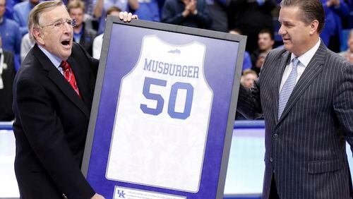 Veteran broadcaster Brent Musburger, left, is presented with a framed jersey in honor of his retirement by Kentucky head coach John Calipari prior to an NCAA college basketball game between Kentucky and Georgia, Tuesday, Jan. 31, 2017, in Lexington, Ky. The game marks Musburger's last broadcast. (AP Photo/James Crisp)