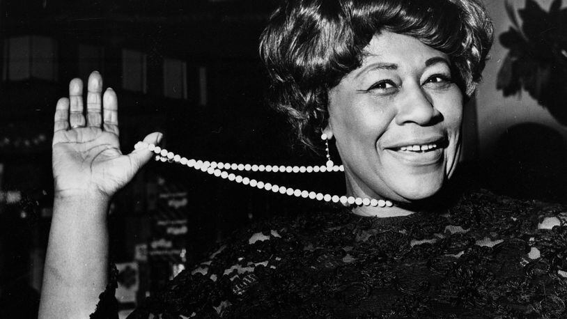 In this Feb. 22, 1968 file photo, American jazz singer Ella Fitzgerald swings her necklace as she arrives at the Carlton Theatre in London, England. The National Portrait Gallery is putting up a photograph of Fitzgerald, often referred to as "The First Lady of Song." The portrait is on view beginning Thursday, April 13, 2017, ahead of the 100th anniversary of Fitzgerald's birth. Fitzgerald, who died in 1996 at the age of 79, would have celebrated her 100th birthday April 25. (AP Photo/Bob Dear, File)