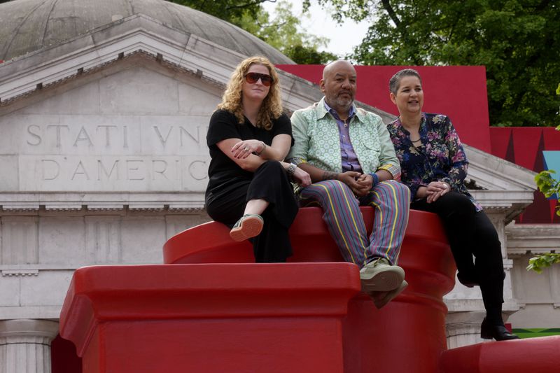 From left, Curator Abigail Winograd, artist Jeffrey Gibson, and Curator Kathleen Ash-Milby pose at the US pavilion during the media open day at the 60th Biennale of Arts in Venice, Italy, Tuesday, April 16, 2024. A Mississippi Choctaw of Cherokee descent, Gibson is the first Native American to represent the United States solo at the Venice Biennale, the world’s oldest contemporary art show. Gibson mixes Western modernism and Native American craft in his vibrantly hued paintings and sculptures. (AP Photo/Luca Bruno)