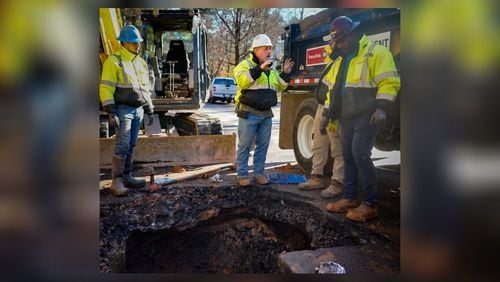 Crews talk about cleaning up before leaving after successfully installing a repair clamp to a burst water main on Woodley drive in Atlanta. Tuesday, December 27 2022 (Ben Hendren for the Atlanta Journal-Constitution)