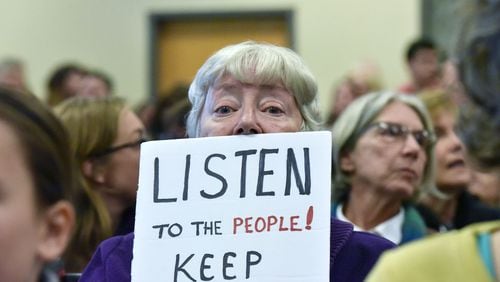 A protester holds a sign during a "constituent service day" for U.S. Sens. David Perdue and Johnny Isakson and Rep. Jody Hice in Greensboro in February. HYOSUB SHIN / HSHIN@AJC.COM