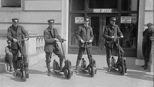 Postmen pose on motorized scooters in an unidentified city circa 1915.