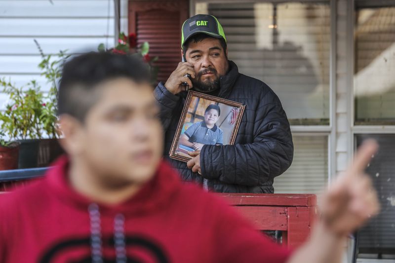 October 16, 2020 Clayton County: Santiago Zavala (center) holds a photo of his slain 13-year old son Brayan on Friday, Oct. 16, 2020 as Jesus Zavala (left) said he had no warning before his 13-year-old brother was shot and killed in front of him Thursday night in their front yard in Clayton County. The two were working on a lawn mower outside their home on Willow Lane, located in a mobile home community off Ga. 85 outside Riverdale. The elder brother barely noticed when a Chevrolet HHR pulled up to his neighbor’s house and a man climbed out, he said. “The shooter didn’t even say I want your money, or this is a robbery or I’m assaulting you,” Zavala, 16, told The Atlanta Journal-Constitution from outside his home on Friday. “He just came, stood there (in) silence and shot my brother. Just for killing.” Brayan Zavala was dead when Clayton County police officers arrived about 9:15 p.m. The Kendrick Middle School student was not a troublemaker, his brother said. He was a typical kid who spent most days with his family since the start of the coronavirus pandemic. Work, then home. Homework, then rest.A Clayton County police spokesman on Thursday said investigators have yet to determine a connection between Brayan and the gunman. Investigators collected evidence at the mobile home park community overnight and declined to provide more information at the scene, Channel 2 Action News reported. The family has started a GoFundMe fundraiser to take Brayan’s body back to Mexico to be buried. (John Spink / John.Spink@ajc.com)