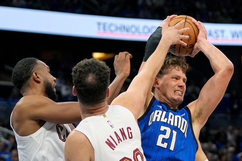 Orlando Magic center Moritz Wagner (21) grabs an offensive rebound away from Cleveland Cavaliers forward Evan Mobley, left, and forward Georges Niang during the second half of Game 6 of an NBA basketball first-round playoff series, Friday, May 3, 2024, in Orlando, Fla. (AP Photo/John Raoux)