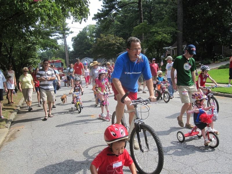 Chris Brinson rides his bicycle in the parade kicking off the 50th annual Fourth of July festivities in the Pine Glen neighborhood near Decatur in 2012, with his son Nicholas in the red helmet in front of him. CONTRIBUTED BY CHRIS BRINSON