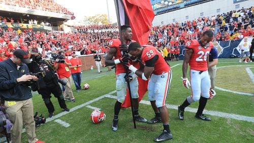 Georgia players plant the Georgia flag in Grant Field after beating Georgia Tech 13-7 in a football game on Saturday, Nov. 28, 2015, in Atlanta. Curtis Compton / ccompton@ajc.com