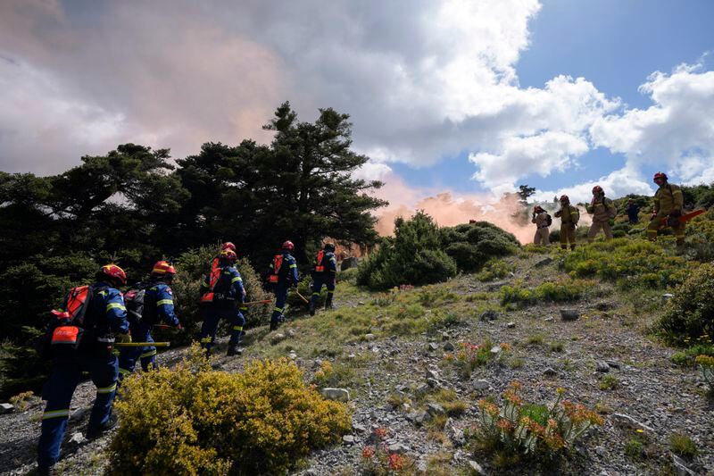 Firefighters of the 1st Wildfire Special Operation Unit, left, and firefighters in training for the special unit, take part in a drill in Villia village some 60 kilometers (37 miles) northwest of Athens, Greece, Friday, April 19, 2024. Greece's fire season officially starts on May 1 but dozens of fires have already been put out over the past month after temperatures began hitting 30 degrees Celsius (86 degrees Fahrenheit) in late March. This year, Greece is doubling the number of firefighters in specialized units to some 1,300, adopting tactics from the United States to try and outflank fires with airborne units scrambled to build breaks in the predicted path of the flames. (AP Photo/Thanassis Stavrakis)