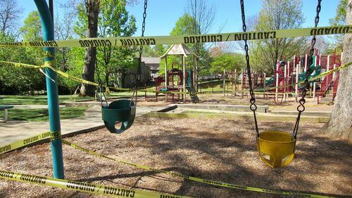 The tennis courts, ball field and dog park are now closed at Lewis Park in Marietta, where a newly posted sign notes new hours and social distancing guidelines. Caution tape blocks use of swings and other playground equipment. Photos: Jennifer Brett, jbrett@ajc.com