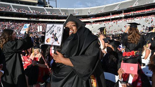 University of Georgia graduates Analla Reid (left) and Danielle Obiri hug before the 2022 Spring Undergraduate Commencement at Sanford Stadium in Athens on Friday, May 13, 2022. The school conferred more than 13,000 awards, certificates and degrees during a recent 12-month stretch. (Hyosub Shin / Hyosub.Shin@ajc.com)