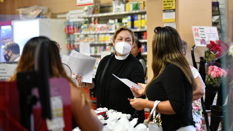 The Rev. Irma Guerra (center), shown at Super Mercado Jalisco supermarket in Norcross on Wednesday, Aug. 11, 2021, hands out a COVID-19 vaccine pamphlet to encourage people in the Hispanic community to get the vaccine. Guerra, who leads the Hispanic ministry at Christ Church Episcopal, has become very involved in vaccine activism. (Hyosub Shin / Hyosub.Shin@ajc.com)