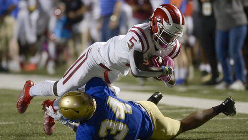 McEachern defensive back Victor Okafor (24) makes a tackle on Hillgrove wide receiver Braylen Howard (5) as he runs the ball in the first half of Friday's game at McEachern.