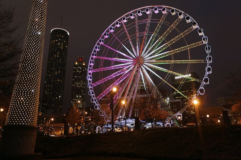 The SkyView Ferris wheel lights up the corner of Luckie Street and Centennial Olympic Park Drive at night. The streetcar has a stop just across the street. BEN GRAY / BGRAY@AJC.COM