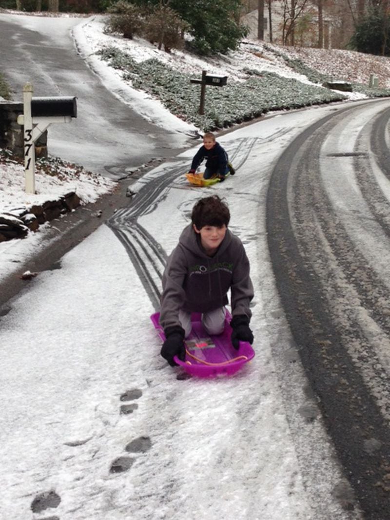 Patrick Clarke, 11, and a friend make the most of this unexpected snow day by sledding down the icy hills in their East Cobb neighborhood. JAIME SARRIO / JSARRIO@AJC.COM