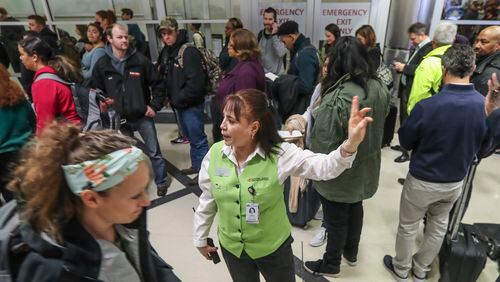 January 14, 2019 Atlanta: Customer Service's Magda Lambo (center) directs travelers as security lines at Hartsfield-Jackson International Airport stretched more than an hour long Monday morning, Jan. 14, 2019 causing travelers to miss flights amid the partial federal shutdown. At a time when the worlds busiest airport has its biggest crowds, there were at least six security lanes closed at domestic terminal security checkpoints, while passengers waited in lines that stretched through the terminal and were winding through baggage claim. The long lines signaled staffing shortages at security checkpoints, as TSA officers have been working without pay since the federal shutdown began Dec. 22. Airport officials normally advise travelers to get to the airport two hours before domestic flights, but on Monday morning Hartsfield-Jackson spokesman Andrew Gobeil advised that travelers should consult with their airlines. Travelers may need to get to the airport even earlier due to the long waits. JOHN SPINK/JSPINK@AJC.COM