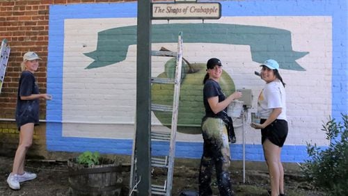 (Right to left) Gabrielle Poteet, Katie Eidson (the project manager) and Alondra Arevalo restored two murals in downtown Milton over the weekend of Aug. 13, 2021. (Photo taken by Robert Meyers of the Milton Historical Society and courtesy of Milton's Facebook page)