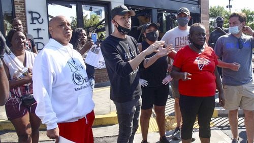 Atlanta councilman Antonio Brown introduced legislation that would ban police use of rubber bullets, stun grenades and military style vehicles. Here he (center) speaks to residents Sunday at the Wendy’s where Rayshard Brooks, a 27-year-old Black man, was shot and killed by Atlanta police Friday evening during a struggle in a Wendy’s drive-thru line. Steve Schaefer for the Atlanta Journal Constitution