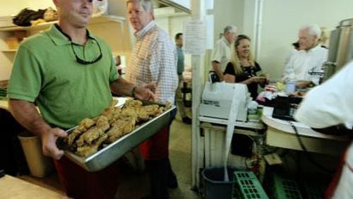 Michael Greene (left) delivers fried pork chops to the cafeteria line at Matthews Cafeteria. His father, owner Charles Greene, is behind him.