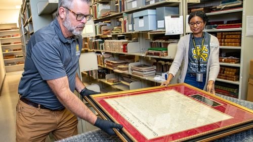 Kennesaw State University’s Tony Howell (left), an exhibit designer, and JoyEllen Williams (right), the curator of the Bentley Rare Book Museum at KSU, prepare to send a rare 1843 copy of the Declaration of Independence to professional conservation on Friday, June 9, 2023.  The historic item is expected to be cleaned and repaired before returning to KSU for display and programming. (Jenni Girtman for The Atlanta Journal-Constitution)