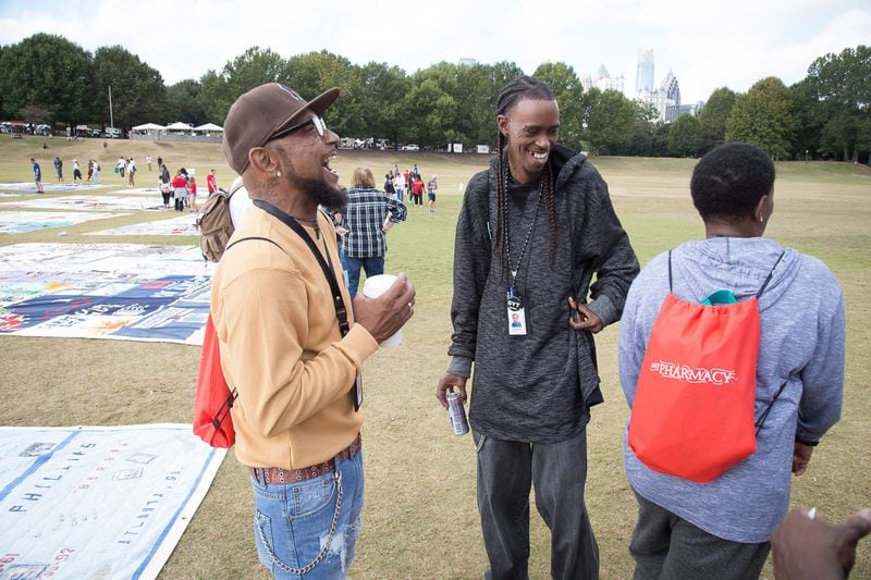Patrick Dent (L) talks with friends near the Aids Memorial Quilt during the 27th Annual AIDS, and 5K Run Sunday at Piedmont Park in Atlanta GA October 22, 2017. STEVE SCHAEFER / SPECIAL TO THE AJC