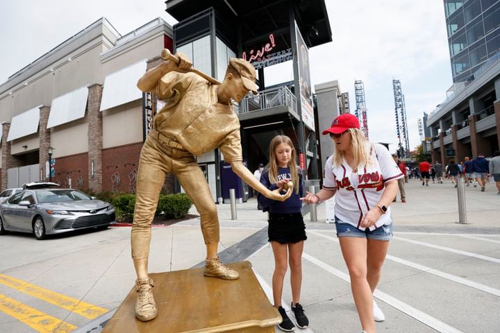 Drea Wray and Aubrey Wray interact with a street performer by Battery Park prior to the first of the National League Division Series on Tuesday, October 11, 2022.  Miguel Martinez / miguel.martinezjimenez@ajc.com