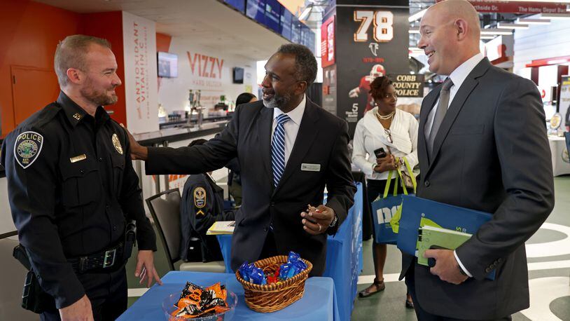 Army veteran Aaron Poulin, right, speaks with Bill Tanks, of the City of Powder Springs public services, center, and Captain Anthony Stallings, of Powder Springs Police, during a Veterans Job Fair at Mercedes-Benz Stadium in September. (Jason Getz / Jason.Getz@ajc.com)